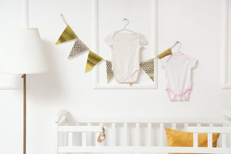Baby bodysuits with flags hanging on light wall in nurseryの写真素材