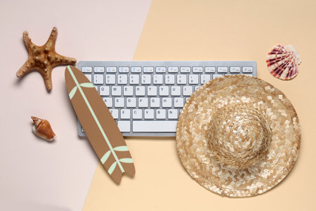 Computer keyboard with hat and beach decor on color backgroundの写真素材