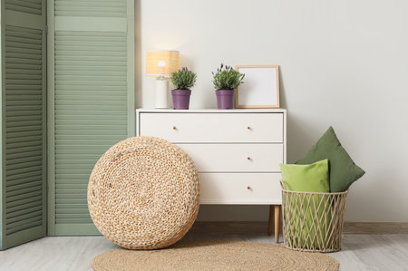 Interior of living room with lavender flowers on commode, pouf and folding screenの写真素材