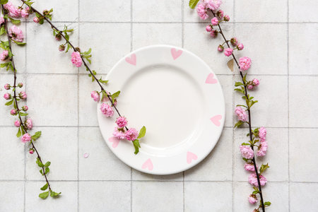 Beautiful table setting with pink blooming branches on white tile background