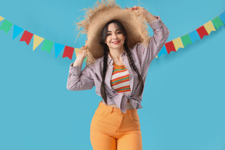 Young happy woman in straw hat and flags on blue background. Festa Junina celebrationの写真素材