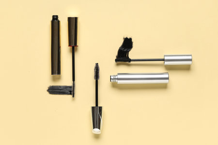 Black mascaras with smears on yellow background
