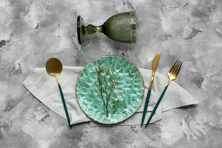 Beautiful table setting with golden cutlery and gypsophila flowers on gray grunge backgroundの写真素材