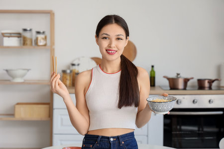 Young Asian woman with tasty ramen in kitchenの写真素材
