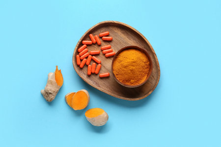 Composition with turmeric powder and pills on blue background, top viewの写真素材