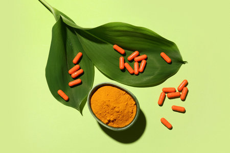 Turmeric powder and pills on green background, top viewの写真素材