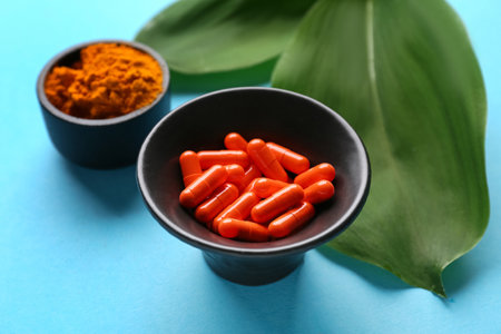 Bowls with turmeric powder and pills on blue backgroundの写真素材