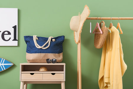 Table with sunglasses, handbag and clothes rack in stylish room, closeup