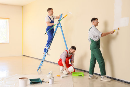 Team of male decorators painting wall in roomの写真素材