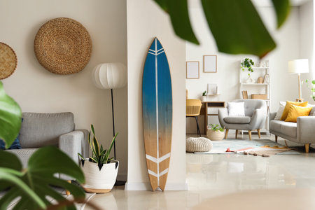 Interior of stylish living room with gray sofa, houseplants and surfboardの写真素材