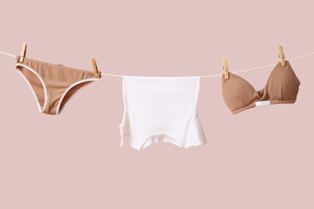 Clean underwear hanging on rope against color wall