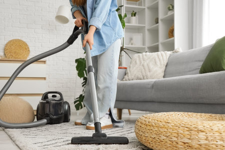 Young woman vacuum cleaning carpet in living room