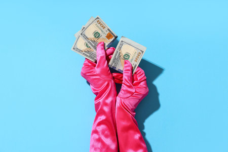 Female hands in gloves with one hundred dollar banknotes on blue background