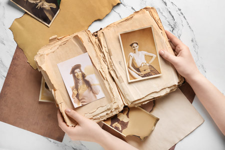 Female hands with old album and photos of relatives on white background. Concept of family treeの写真素材