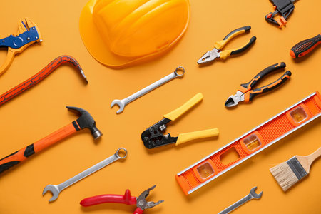 Hardhat and construction tools on orange backgroundの写真素材