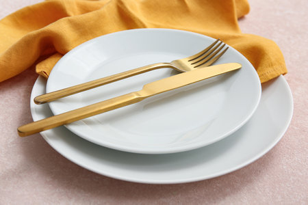 Beautiful table setting with golden cutlery on beige background, closeupの写真素材