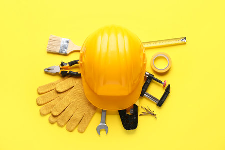 Hardhat, gloves and construction tools on yellow backgroundの写真素材