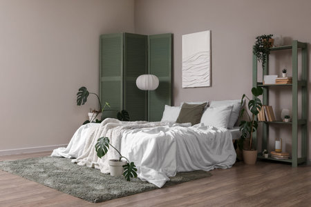 Interior of bedroom with green folding screen, shelf unit and plants