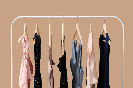 Different female dresses hanging on rack against color backgroundの写真素材