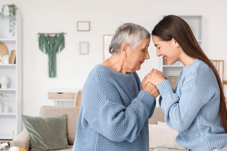 Happy young woman with her grandmother holding hands at home