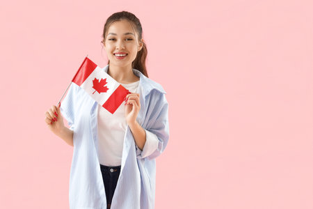 Young Asian woman with flag of Canada on pink backgroundの写真素材