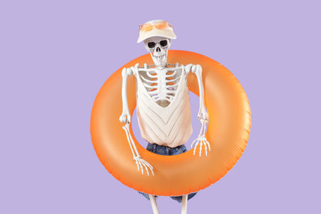 Human skeleton with clothes and swim ring on lilac background. Summer vacation conceptの写真素材