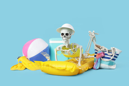 Human skeleton with beach accessories lying on blue background. Summer vacation conceptの写真素材