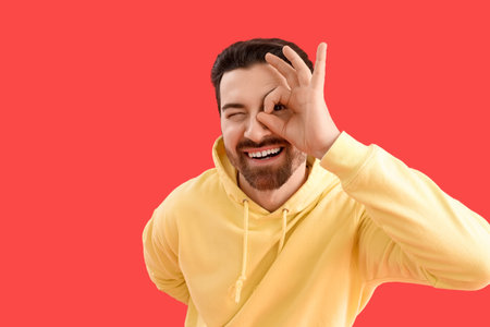 Young man showing OK on red backgroundの写真素材