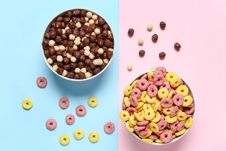 Bowls with chocolate corn balls and color cereal rings on color background, closeup