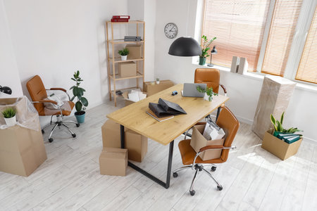Interior of office with workplace, plants and cardboard boxes on moving dayの写真素材