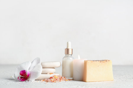 Spa composition with bottle of essential oil, burning candle and sea salt on light backgroundの写真素材