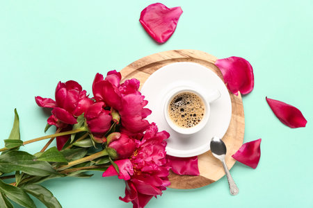 Beautiful peony flowers and cup of hot coffee on turquoise backgroundの写真素材