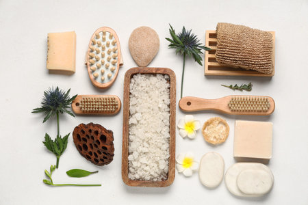 Composition with sea salt, spa accessories and tropical flowers on light background
