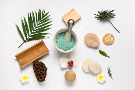 Composition with mortar of sea salt, spa accessories and flowers on light background