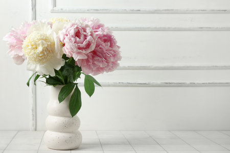 Vase with beautiful peony flowers on white tile tableの写真素材