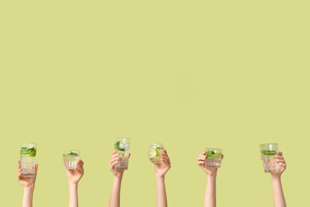 Female hands with different glasses of fresh mojito on green backgroundの写真素材