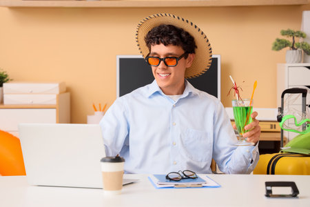 Young businessman with cocktail using laptop in office. Summer vacationの写真素材