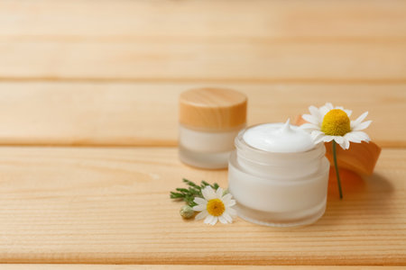 Jars of chamomile cosmetic cream and flowers on wooden backgroundの写真素材