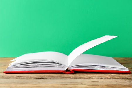 Open book on wooden table against green backgroundの写真素材