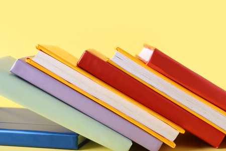 Many colorful books on yellow background, closeupの写真素材