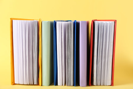 Row of colorful books on yellow backgroundの写真素材