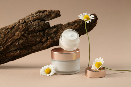 Composition with jars of natural cream, chamomile flowers and tree bark on color backgroundの写真素材