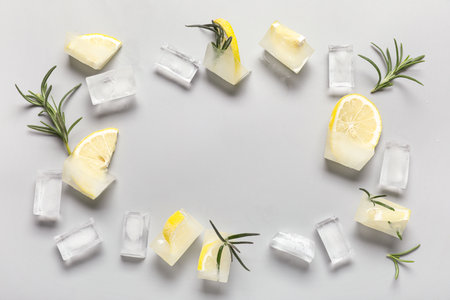 Frame made of frozen lemon in ice cubes with rosemary on gray backgroundの写真素材