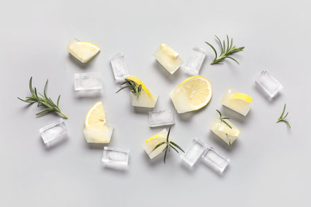Slices of frozen lemon in ice cubes with rosemary on gray backgroundの写真素材