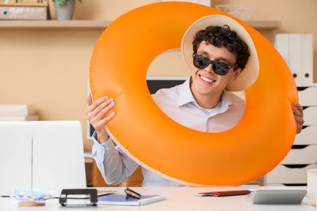 Young businessman with swim ring waiting for summer vacation in officeの写真素材