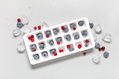 Tray with fresh berries and ice cubes on gray backgroundの写真素材