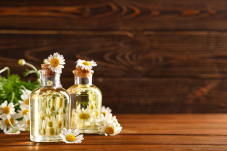 Bottles of chamomile cosmetic oil and flowers on wooden backgroundの写真素材
