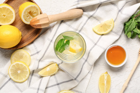 Glass of fresh lemonade with mint and bowl of sweet honey on white backgroundの写真素材
