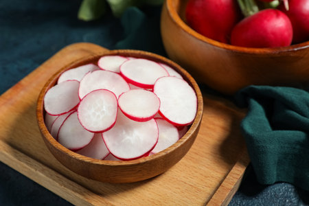 Wooden bowls with fresh radishes on dark backgroundの写真素材