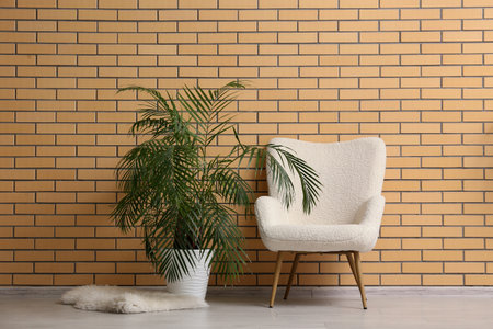 Armchair with palm plant near brick wall in roomの写真素材